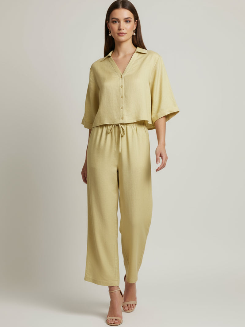 Vestido midi de tejido ligero, cuello en V con cordones y manga 3/4; silueta relajada tipo túnica con caída fluida y textura sutil—elegante y versátil de día a noche