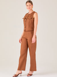 Este pantalón presenta un corte de pierna ancha y recta, confeccionado en una tela estructurada de tono marrón cálido. Tiene un diseño elegante y minimalista, con cintura de talle medio y cierre delantero oculto. Las líneas limpias y la ausencia de detalles recargados lo hacen ideal para un look pulido y sofisticado. Incluye bolsillos discretos laterales y se ajusta ligeramente en la cadera, cayendo con amplitud hasta los tobillos. Su estilo versátil lo convierte en una prenda perfecta tanto para contextos 