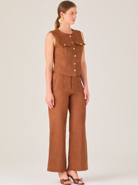 Este pantalón presenta un corte de pierna ancha y recta, confeccionado en una tela estructurada de tono marrón cálido. Tiene un diseño elegante y minimalista, con cintura de talle medio y cierre delantero oculto. Las líneas limpias y la ausencia de detalles recargados lo hacen ideal para un look pulido y sofisticado. Incluye bolsillos discretos laterales y se ajusta ligeramente en la cadera, cayendo con amplitud hasta los tobillos. Su estilo versátil lo convierte en una prenda perfecta tanto para contextos 