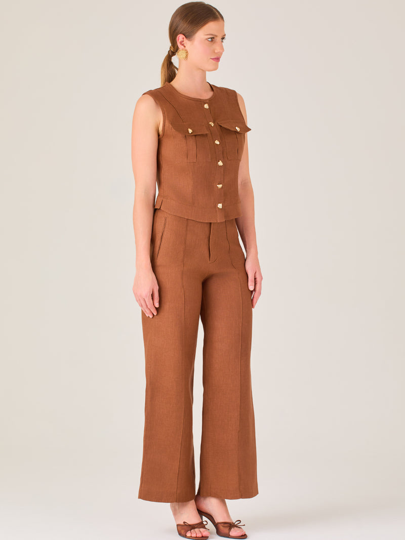 Este pantalón presenta un corte de pierna ancha y recta, confeccionado en una tela estructurada de tono marrón cálido. Tiene un diseño elegante y minimalista, con cintura de talle medio y cierre delantero oculto. Las líneas limpias y la ausencia de detalles recargados lo hacen ideal para un look pulido y sofisticado. Incluye bolsillos discretos laterales y se ajusta ligeramente en la cadera, cayendo con amplitud hasta los tobillos. Su estilo versátil lo convierte en una prenda perfecta tanto para contextos 