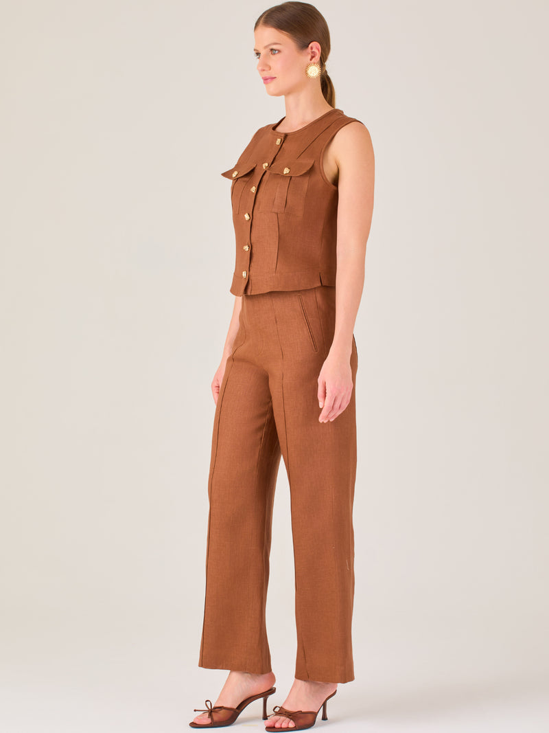 Este pantalón presenta un corte de pierna ancha y recta, confeccionado en una tela estructurada de tono marrón cálido. Tiene un diseño elegante y minimalista, con cintura de talle medio y cierre delantero oculto. Las líneas limpias y la ausencia de detalles recargados lo hacen ideal para un look pulido y sofisticado. Incluye bolsillos discretos laterales y se ajusta ligeramente en la cadera, cayendo con amplitud hasta los tobillos. Su estilo versátil lo convierte en una prenda perfecta tanto para contextos 