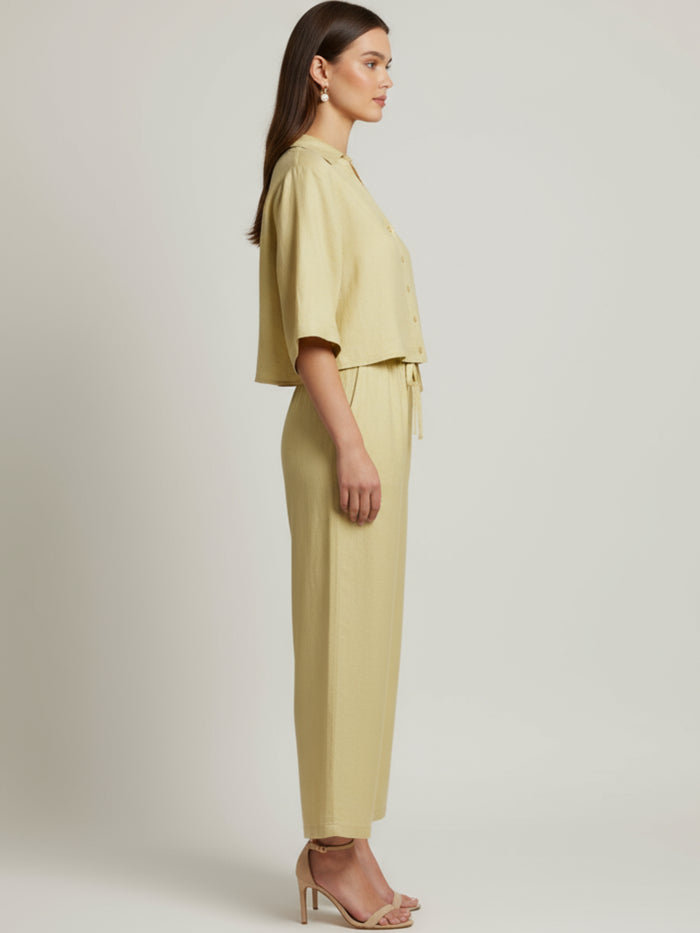 Vestido midi de tejido ligero, cuello en V con cordones y manga 3/4; silueta relajada tipo túnica con caída fluida y textura sutil—elegante y versátil de día a noche