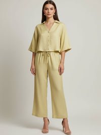 Vestido midi de tejido ligero, cuello en V con cordones y manga 3/4; silueta relajada tipo túnica con caída fluida y textura sutil—elegante y versátil de día a noche
