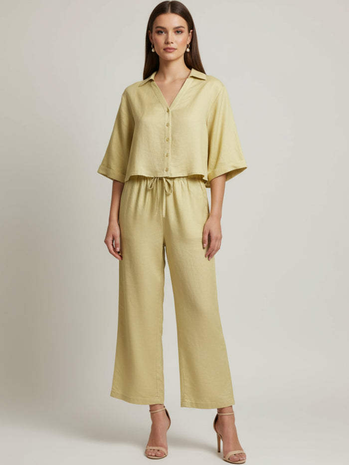 Vestido midi de tejido ligero, cuello en V con cordones y manga 3/4; silueta relajada tipo túnica con caída fluida y textura sutil—elegante y versátil de día a noche
