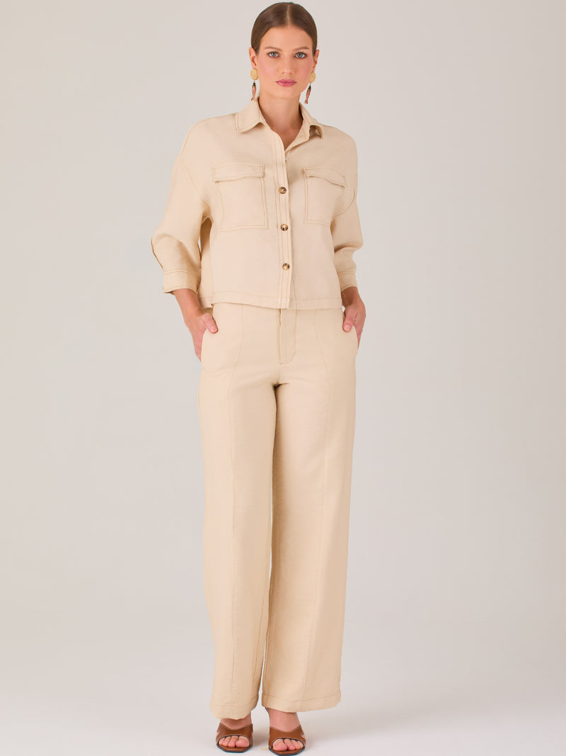 Este pantalón tiene un diseño sofisticado y moderno, confeccionado en un tono beige claro muy versátil. Presenta una silueta de pierna recta y ligeramente amplia, lo que aporta una caída elegante y cómoda. La cintura es de talle medio-alto, con cierre delantero oculto y detalles de pinzas que estilizan la figura. Incluye trabillas para cinturón y bolsillos laterales funcionales, además de costuras marcadas al frente que aportan estructura. Es una prenda ideal para looks de oficina, conjuntos monocromáticos 