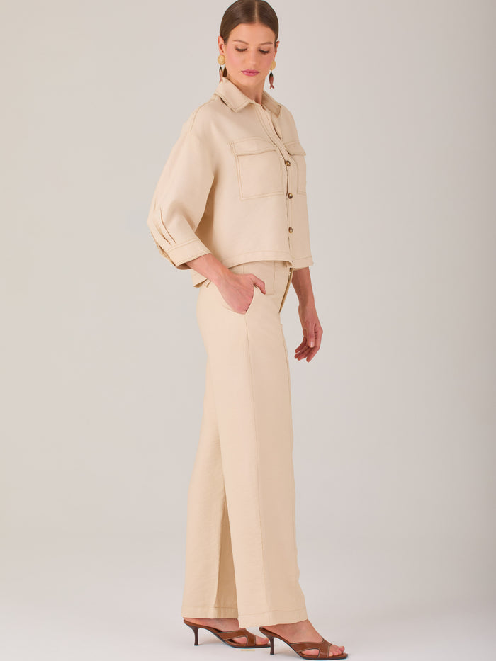 Este pantalón tiene un diseño sofisticado y moderno, confeccionado en un tono beige claro muy versátil. Presenta una silueta de pierna recta y ligeramente amplia, lo que aporta una caída elegante y cómoda. La cintura es de talle medio-alto, con cierre delantero oculto y detalles de pinzas que estilizan la figura. Incluye trabillas para cinturón y bolsillos laterales funcionales, además de costuras marcadas al frente que aportan estructura. Es una prenda ideal para looks de oficina, conjuntos monocromáticos 
