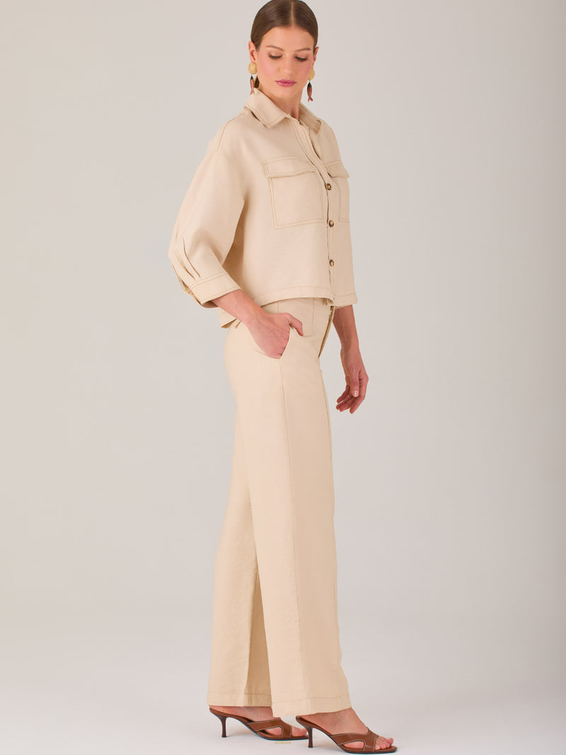 Este pantalón tiene un diseño sofisticado y moderno, confeccionado en un tono beige claro muy versátil. Presenta una silueta de pierna recta y ligeramente amplia, lo que aporta una caída elegante y cómoda. La cintura es de talle medio-alto, con cierre delantero oculto y detalles de pinzas que estilizan la figura. Incluye trabillas para cinturón y bolsillos laterales funcionales, además de costuras marcadas al frente que aportan estructura. Es una prenda ideal para looks de oficina, conjuntos monocromáticos 