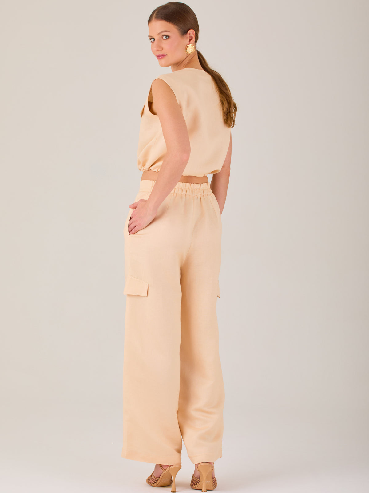 Este pantalón de corte recto y silueta ancha tiene un diseño tipo cargo, con bolsillos de solapa a los costados de las piernas que aportan un toque utilitario. La pretina combina funcionalidad y estilo: es parcialmente elástica en la parte posterior para mayor comodidad, mientras que el frente incluye cierre con botón y pinzas que añaden estructura. Su diseño equilibra lo casual y lo sofisticado, ideal para looks versátiles.