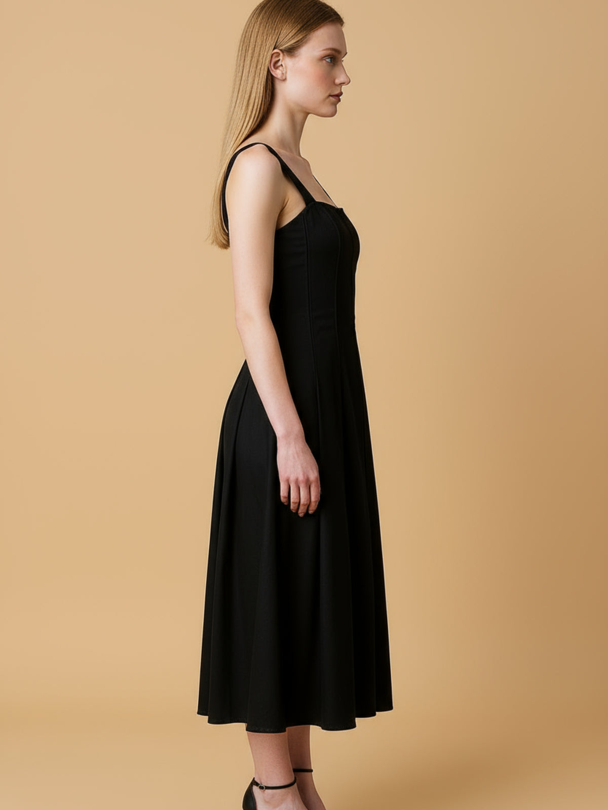 Vestido midi con tirantes anchos y escote recto que enmarca los hombros con elegancia. El cuerpo entallado lleva cortes verticales tipo corsé que definen la silueta, mientras la falda evasé abre con amplitud y movimiento hasta media pantorrilla. Un diseño depurado y femenino, ideal para eventos o noches especiales; combínalo con sandalias de tacón y joyería mínima para un look impecable