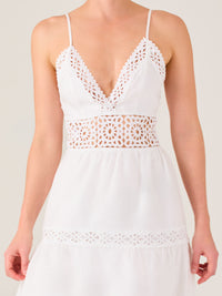 Este vestido largo blanco tiene un estilo fresco, romántico y veraniego. Cuenta con finos tirantes y un escote en “V” pronunciado, delicadamente adornado con bordado tipo encaje floral que continúa en la cintura, generando un efecto de transparencia sutil y elegante.

La falda de corte amplio y largo midi cae suavemente desde la cintura, con detalles de franjas horizontales de bordado calado que repiten el motivo floral. El tejido ligero y vaporoso aporta comodidad y libertad de movimiento.