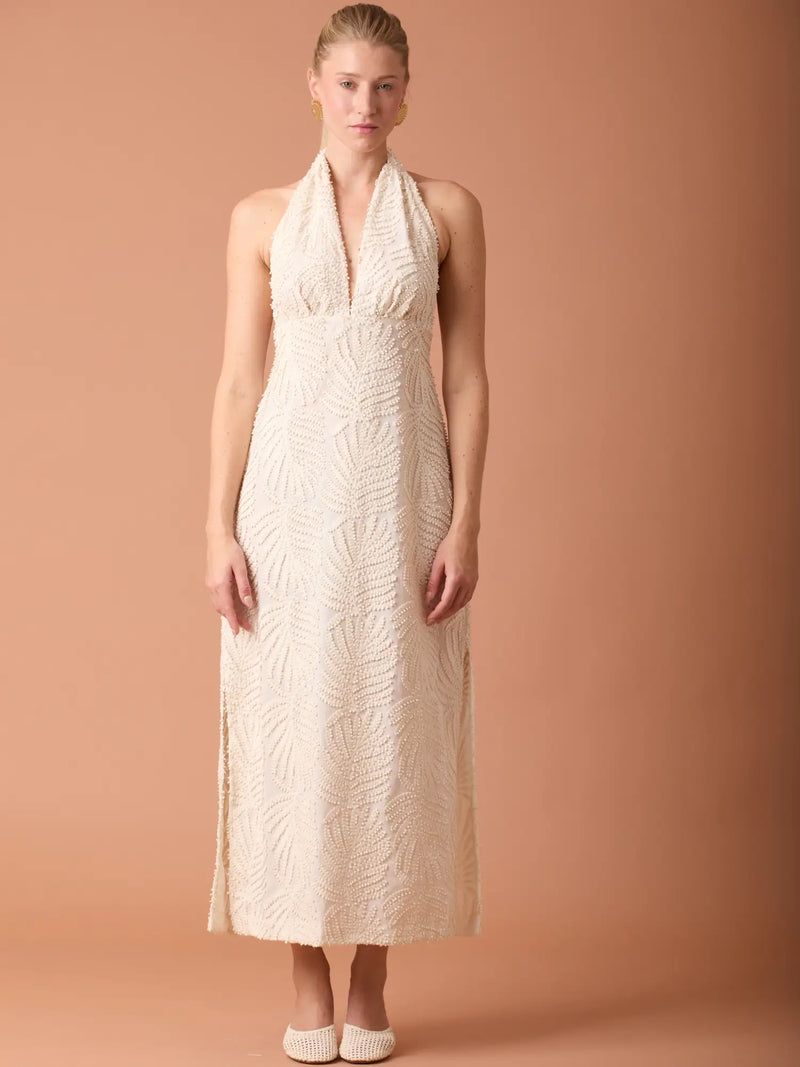 Vestido largo beige con cuello halter y textura en relieve, ideal para ocasiones elegantes.