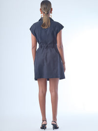 Vestido corto de estilo camisero con botones grandes al frente. Cuenta con cuello clásico, mangas cortas tipo casquillo y bolsillos de parche en el pecho y la parte baja del frente, que aportan un aire utilitario. La cintura se ajusta con un cinturón del mismo tejido, creando una silueta definida. Su diseño combina funcionalidad y sofisticación de manera equilibrada.

Detalles:

Color: Negro