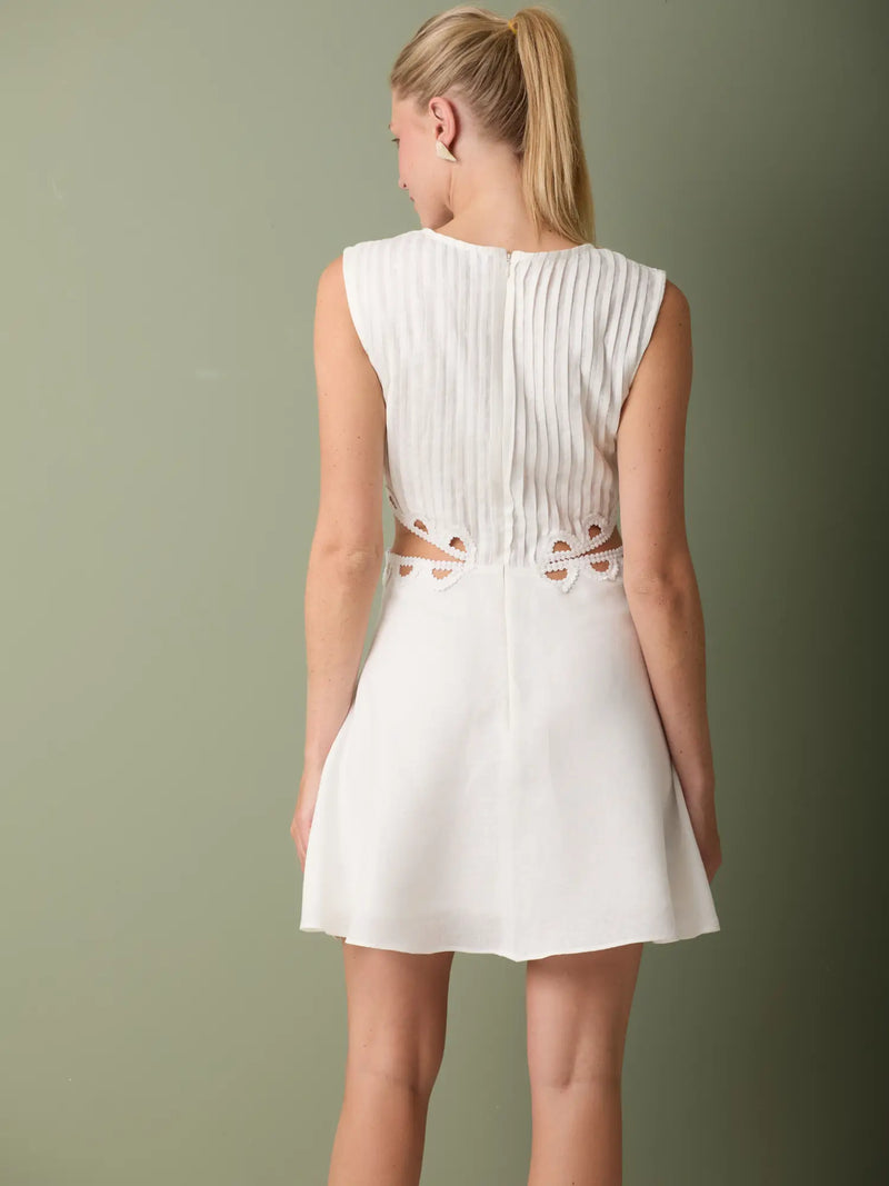 Vestido corto blanco con detalles bordados en los recortes y estilo femenino y sofisticado.