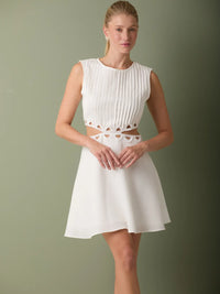 Vestido moderno blanco corto con plisado frontal y silueta ligera ideal para ocasiones especiales.