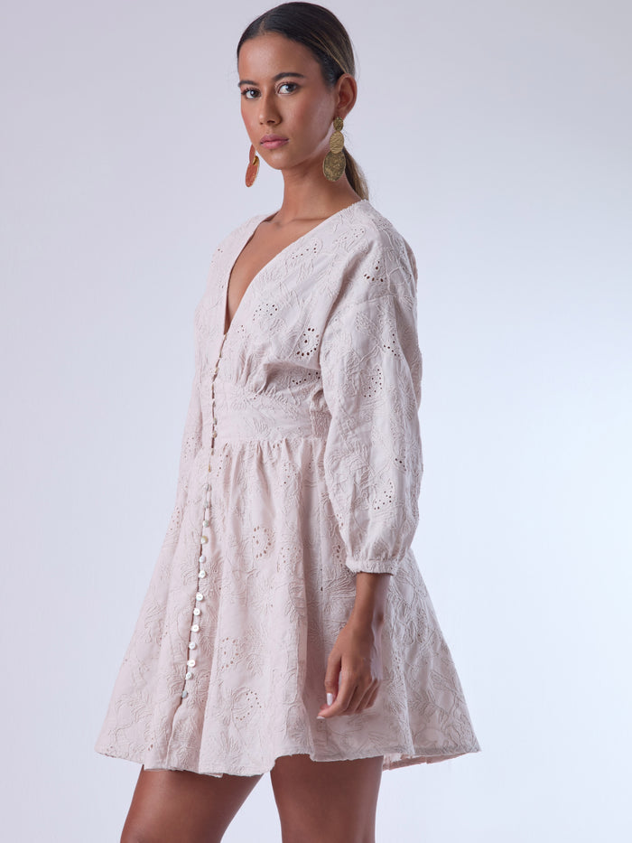 Este vestido de silueta femenina combina un escote en V profundo con una cintura marcada que estiliza la figura. Con mangas 3/4 ligeramente abullonadas y delicados detalles bordados, es una prenda ideal para ocasiones especiales de día o eventos semi formales. Su botonadura frontal añade un toque romántico y clásico que realza su diseño atemporal.