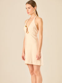 Vestido corto en tono crema de silueta ajustada con escote halter profundo que se adorna con un original detalle de argollas decorativas en el centro del busto, creando un sutil efecto de abertura. Su diseño minimalista con acento sensual lo convierte en una prenda ideal para ocasiones especiales con un toque moderno y sofisticado.

Color: Sand