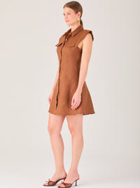 Este vestido sin mangas tiene un diseño camisero de corte recto con estructura entallada en la parte superior que se ajusta a la silueta. Tiene cuello tipo camisa y una botonadura completa al frente con botones grandes y visibles. A la altura del pecho, incluye dos bolsillos de parche con solapa, añadiendo un detalle funcional y decorativo. La falda tiene una caída en línea A, que da un toque femenino y ligeramente acampanado. La parte trasera mantiene la sencillez con costuras que definen la forma del vest