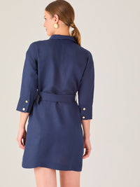 Vestido tipo camisero corto, con cuello clásico, mangas tres cuartos, botones frontales y cinturón con hebilla dorada. Estilo elegante y casual.