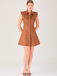 Este vestido sin mangas tiene un diseño camisero de corte recto con estructura entallada en la parte superior que se ajusta a la silueta. Tiene cuello tipo camisa y una botonadura completa al frente con botones grandes y visibles. A la altura del pecho, incluye dos bolsillos de parche con solapa, añadiendo un detalle funcional y decorativo. La falda tiene una caída en línea A, que da un toque femenino y ligeramente acampanado. La parte trasera mantiene la sencillez con costuras que definen la forma del vest