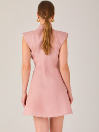 Este vestido sin mangas tiene un diseño camisero de corte recto con estructura entallada en la parte superior que se ajusta a la silueta. Tiene cuello tipo camisa y una botonadura completa al frente con botones grandes y visibles. A la altura del pecho, incluye dos bolsillos de parche con solapa, añadiendo un detalle funcional y decorativo. La falda tiene una caída en línea A, que da un toque femenino y ligeramente acampanado. La parte trasera mantiene la sencillez con costuras que definen la forma del vest