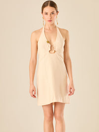 Vestido corto en tono crema de silueta ajustada con escote halter profundo que se adorna con un original detalle de argollas decorativas en el centro del busto, creando un sutil efecto de abertura. Su diseño minimalista con acento sensual lo convierte en una prenda ideal para ocasiones especiales con un toque moderno y sofisticado.

Color: Sand