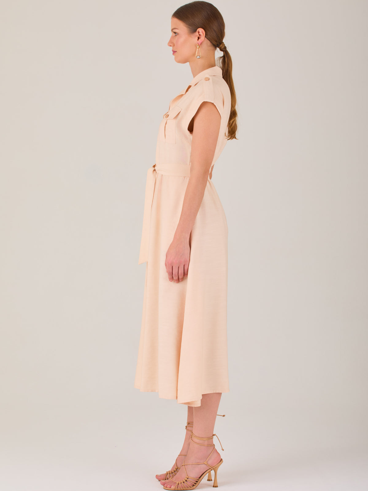 Diseño atemporal con carácter. Este vestido midi sin mangas combina estructura y feminidad con detalles utilitarios como bolsillos frontales, cierre metálico y solapas marcadas. El cinturón en la cintura permite ajustar la silueta, creando un look pulido ideal para la oficina, eventos casuales o estilismos urbanos con elegancia natural.

Detalles: