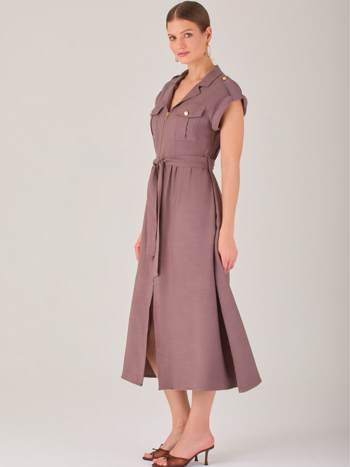 Diseño atemporal con carácter. Este vestido midi sin mangas combina estructura y feminidad con detalles utilitarios como bolsillos frontales, cierre metálico y solapas marcadas. El cinturón en la cintura permite ajustar la silueta, creando un look pulido ideal para la oficina, eventos casuales o estilismos urbanos con elegancia natural.