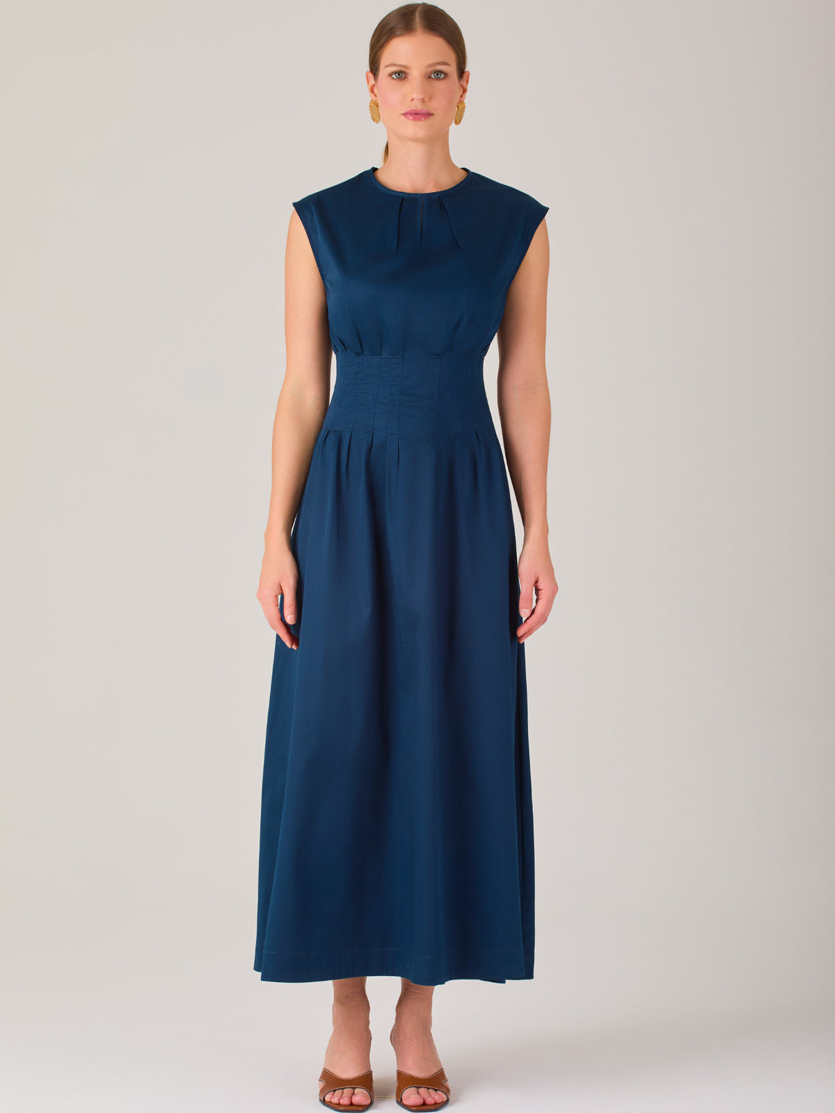 Delicado y femenino, este vestido de largo midi combina una silueta limpia con detalles sutiles. Su diseño sin mangas y escote ligeramente fruncido aporta frescura, mientras que la cintura elástica acentúa la figura con comodidad. Ideal para ocasiones de día, eventos casuales o looks refinados con aire minimalista.