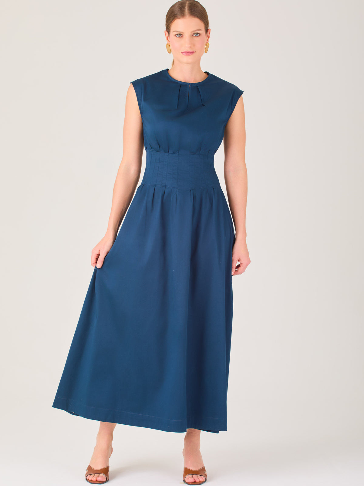 Delicado y femenino, este vestido de largo midi combina una silueta limpia con detalles sutiles. Su diseño sin mangas y escote ligeramente fruncido aporta frescura, mientras que la cintura elástica acentúa la figura con comodidad. Ideal para ocasiones de día, eventos casuales o looks refinados con aire minimalista.