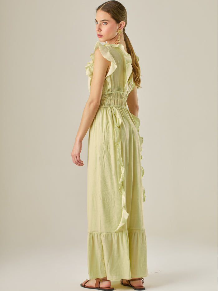 Vestido largo sin mangas con escote en "V" profundo y un diseño con volantes que recorren tanto los tirantes como la parte frontal del busto y la falda. La cintura está fruncida con elástico para dar definición y comodidad, mientras que la falda fluye suavemente con un detalle de volante en el dobladillo, aportando movimiento y un aire femenino al conjunto.