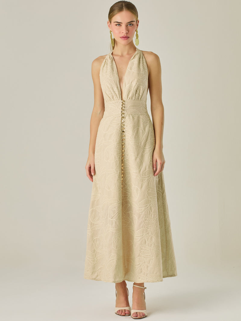 Vestido largo con escote halter profundo y espalda descubierta, ideal para ocasiones especiales. Su diseño sofisticado se realza con detalles bordados y una silueta que estiliza, logrando un look elegante y llamativo con un aire moderno.

Detalles:

Color: Sand

Material: 100% Algodon

Características: Incluye botones.