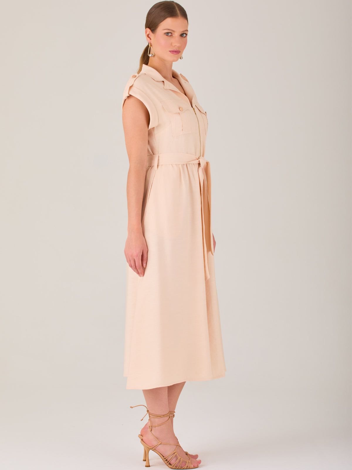 Diseño atemporal con carácter. Este vestido midi sin mangas combina estructura y feminidad con detalles utilitarios como bolsillos frontales, cierre metálico y solapas marcadas. El cinturón en la cintura permite ajustar la silueta, creando un look pulido ideal para la oficina, eventos casuales o estilismos urbanos con elegancia natural.

Detalles: