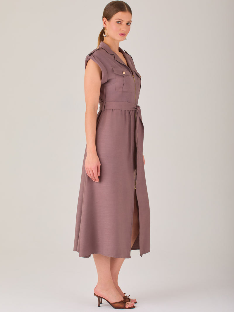 Diseño atemporal con carácter. Este vestido midi sin mangas combina estructura y feminidad con detalles utilitarios como bolsillos frontales, cierre metálico y solapas marcadas. El cinturón en la cintura permite ajustar la silueta, creando un look pulido ideal para la oficina, eventos casuales o estilismos urbanos con elegancia natural.