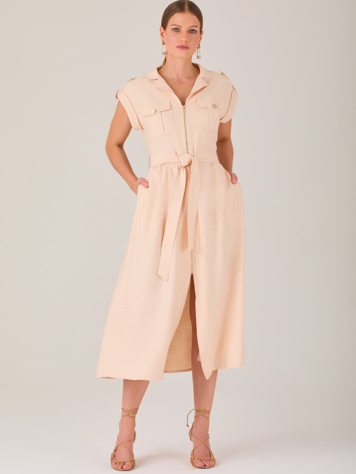 Diseño atemporal con carácter. Este vestido midi sin mangas combina estructura y feminidad con detalles utilitarios como bolsillos frontales, cierre metálico y solapas marcadas. El cinturón en la cintura permite ajustar la silueta, creando un look pulido ideal para la oficina, eventos casuales o estilismos urbanos con elegancia natural.

Detalles: