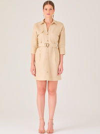 Vestido tipo camisero beige, corto, con cuello clásico, mangas tres cuartos, botones frontales y cinturón con hebilla dorada. Estilo elegante y casual.