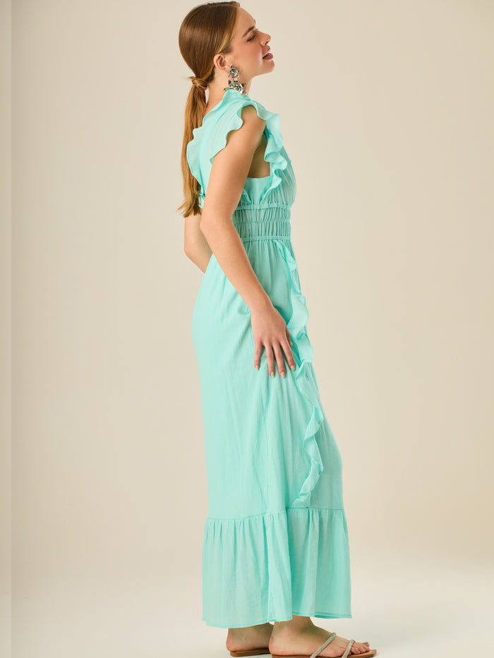 Vestido largo sin mangas con escote en "V" profundo y un diseño con volantes que recorren tanto los tirantes como la parte frontal del busto y la falda. La cintura está fruncida con elástico para dar definición y comodidad, mientras que la falda fluye suavemente con un detalle de volante en el dobladillo, aportando movimiento y un aire femenino al conjunto.