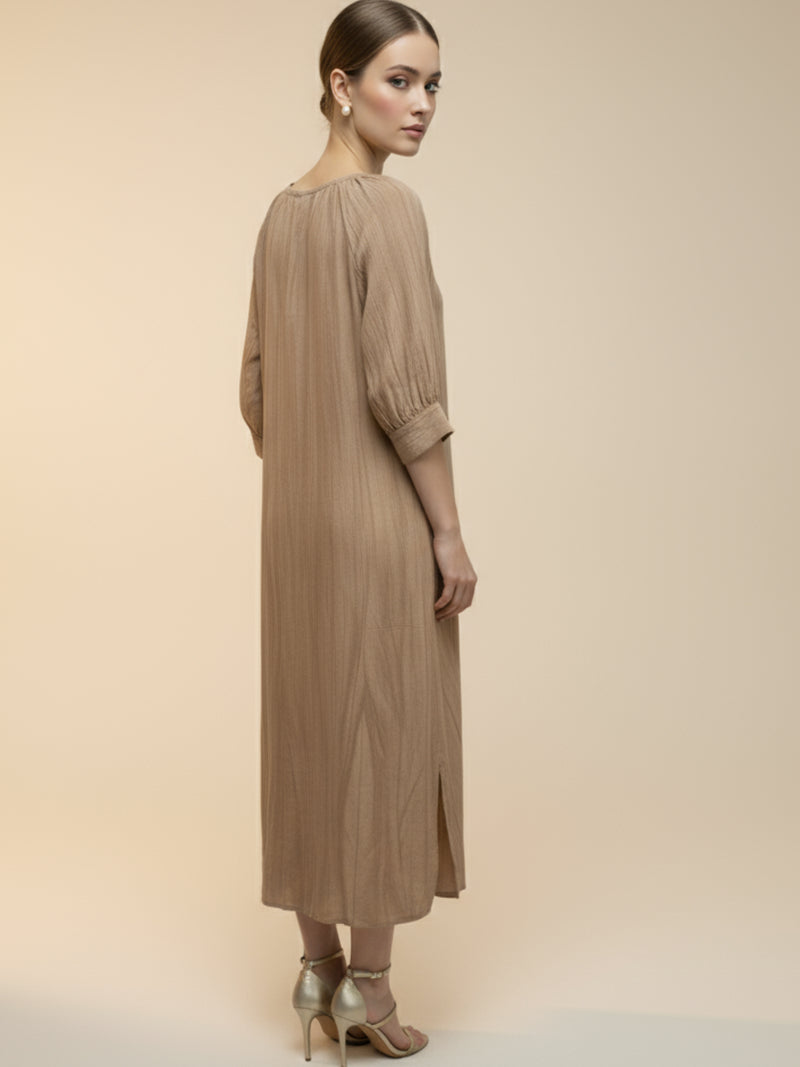 Vestido midi de tejido ligero, cuello en V con cordones y manga 3/4; silueta relajada tipo túnica con caída fluida y textura sutil—elegante y versátil de día a noche