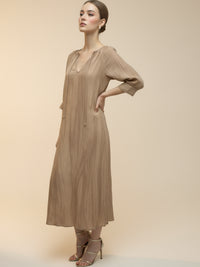 Vestido midi de tejido ligero, cuello en V con cordones y manga 3/4; silueta relajada tipo túnica con caída fluida y textura sutil—elegante y versátil de día a noche