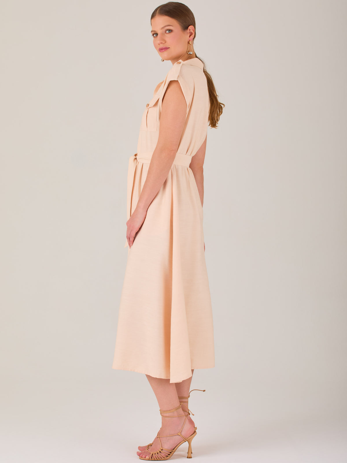 Diseño atemporal con carácter. Este vestido midi sin mangas combina estructura y feminidad con detalles utilitarios como bolsillos frontales, cierre metálico y solapas marcadas. El cinturón en la cintura permite ajustar la silueta, creando un look pulido ideal para la oficina, eventos casuales o estilismos urbanos con elegancia natural.

Detalles: