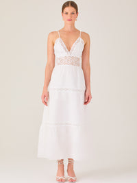 Este vestido largo blanco tiene un estilo fresco, romántico y veraniego. Cuenta con finos tirantes y un escote en “V” pronunciado, delicadamente adornado con bordado tipo encaje floral que continúa en la cintura, generando un efecto de transparencia sutil y elegante.

La falda de corte amplio y largo midi cae suavemente desde la cintura, con detalles de franjas horizontales de bordado calado que repiten el motivo floral. El tejido ligero y vaporoso aporta comodidad y libertad de movimiento.