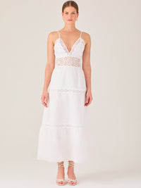 Este vestido largo blanco tiene un estilo fresco, romántico y veraniego. Cuenta con finos tirantes y un escote en “V” pronunciado, delicadamente adornado con bordado tipo encaje floral que continúa en la cintura, generando un efecto de transparencia sutil y elegante.

La falda de corte amplio y largo midi cae suavemente desde la cintura, con detalles de franjas horizontales de bordado calado que repiten el motivo floral. El tejido ligero y vaporoso aporta comodidad y libertad de movimiento.