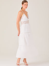 Este vestido largo blanco tiene un estilo fresco, romántico y veraniego. Cuenta con finos tirantes y un escote en “V” pronunciado, delicadamente adornado con bordado tipo encaje floral que continúa en la cintura, generando un efecto de transparencia sutil y elegante.

La falda de corte amplio y largo midi cae suavemente desde la cintura, con detalles de franjas horizontales de bordado calado que repiten el motivo floral. El tejido ligero y vaporoso aporta comodidad y libertad de movimiento.