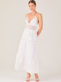 Este vestido largo blanco tiene un estilo fresco, romántico y veraniego. Cuenta con finos tirantes y un escote en “V” pronunciado, delicadamente adornado con bordado tipo encaje floral que continúa en la cintura, generando un efecto de transparencia sutil y elegante.

La falda de corte amplio y largo midi cae suavemente desde la cintura, con detalles de franjas horizontales de bordado calado que repiten el motivo floral. El tejido ligero y vaporoso aporta comodidad y libertad de movimiento.